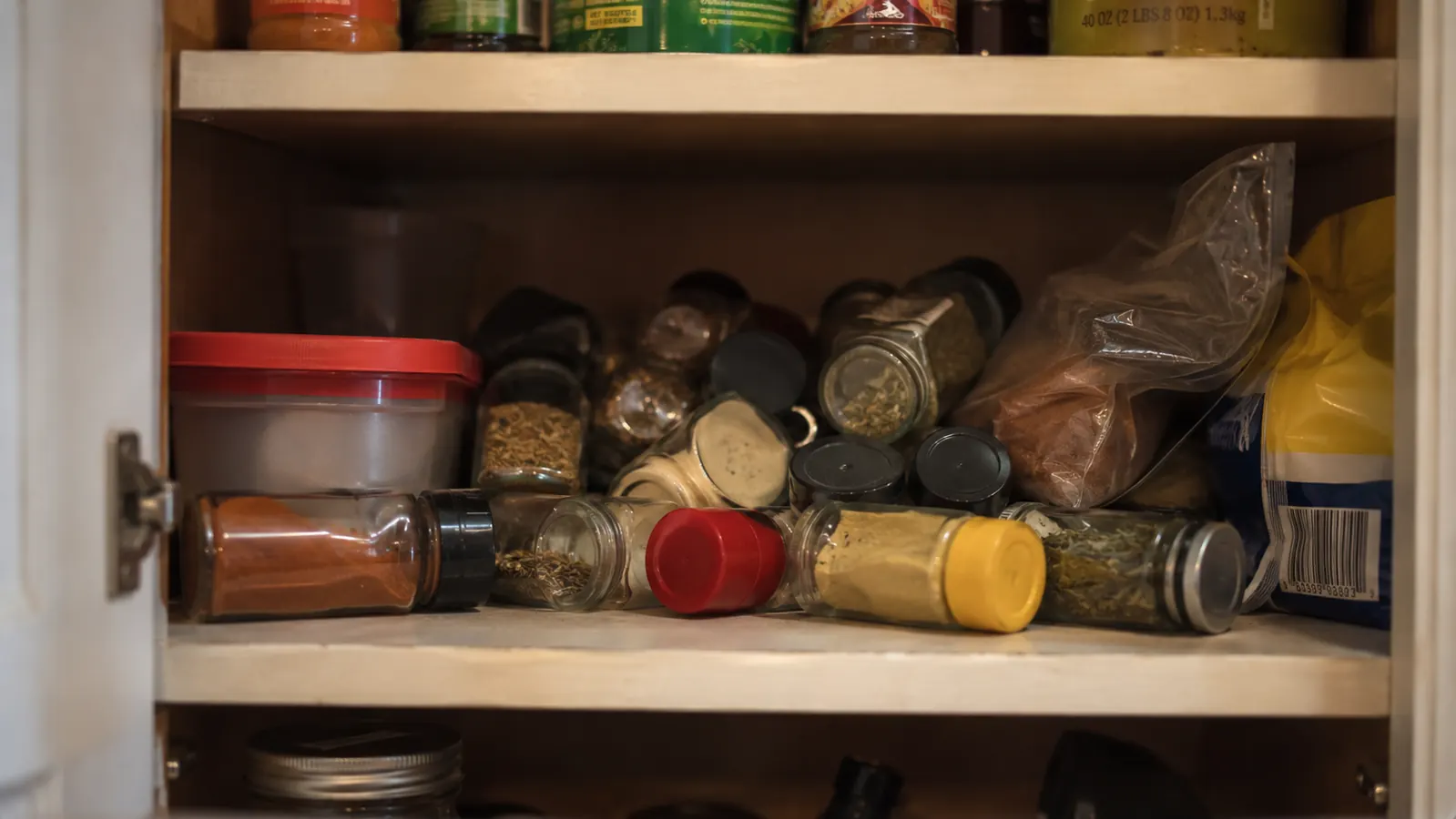 Chaotic spice cabinet with bottles tipped on their sides and stacked randomly